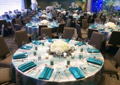 Teal patterned tablecloths with teal napkins on round tables