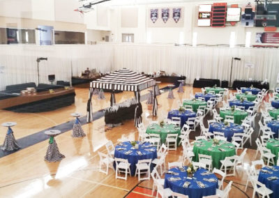 Blue and green linens with striped napkins on round tables with white resin chairs