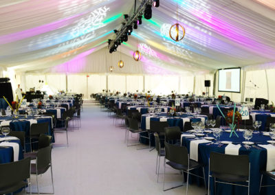 Full tent of corporate event with blue linens on round tables