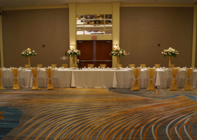 White linens on round tables with acrylic chivari chairs with yellow ribbon