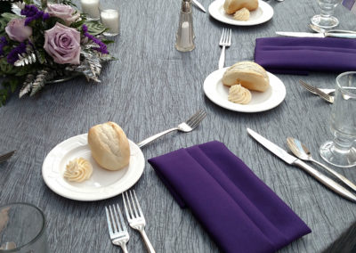Grey crinkle linen on round table with purple napkins