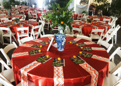 Orange linens on round table with white resin chairs