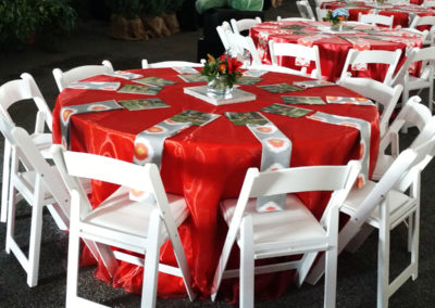 Orange linens on round table with white resin chairs