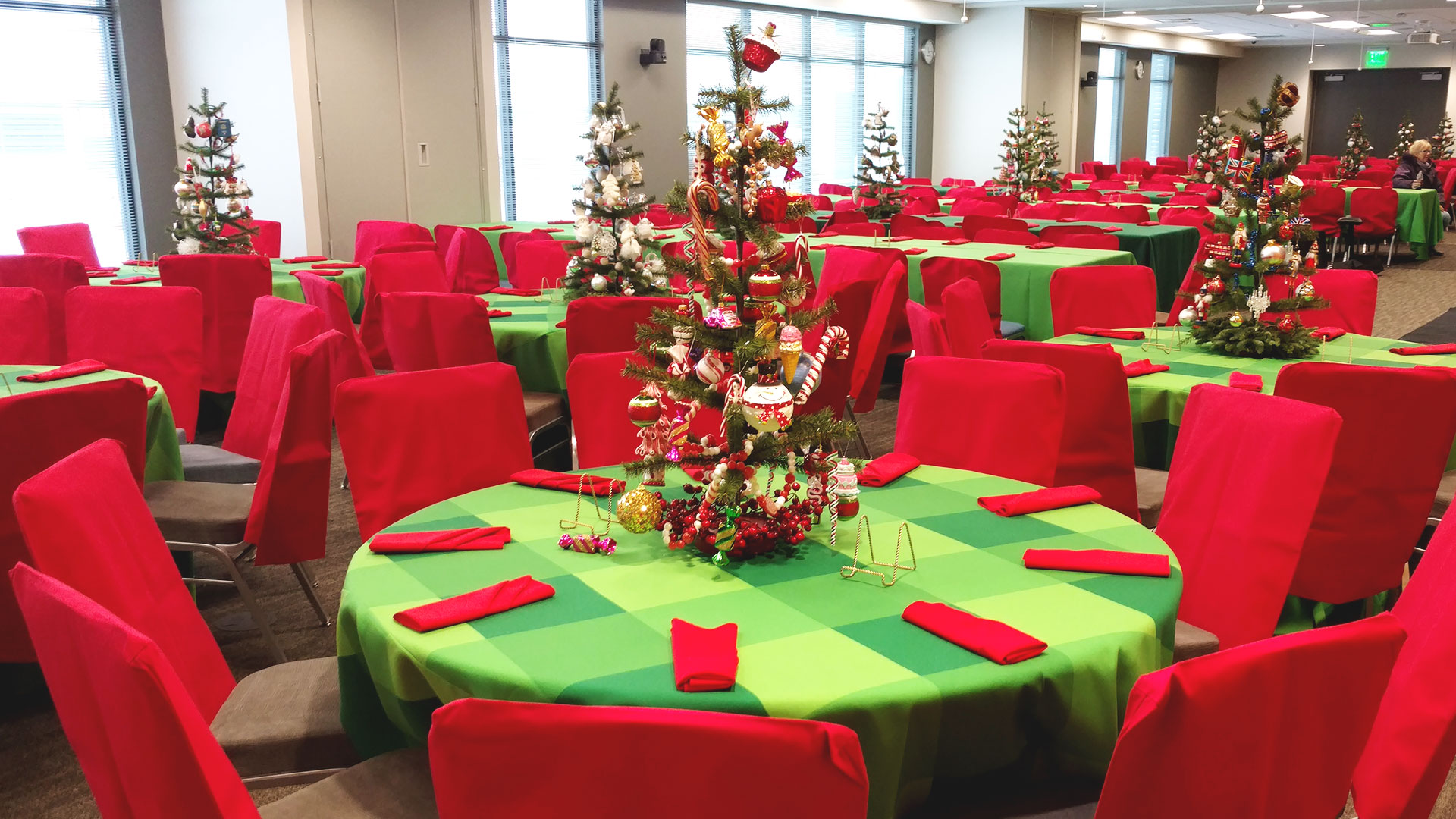 Green plaid tablecloths with red chair covers for holiday event