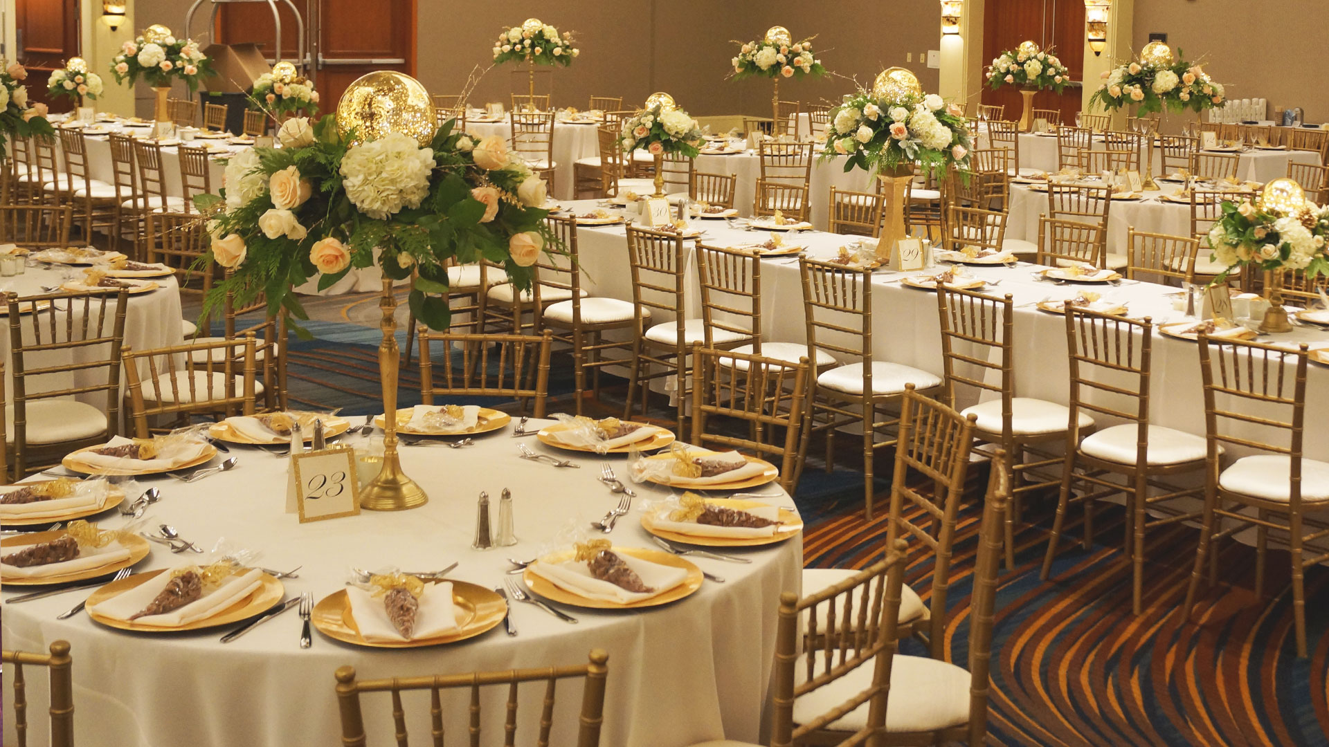Wedding with white linens on round and banquet tables with gold chivari chairs